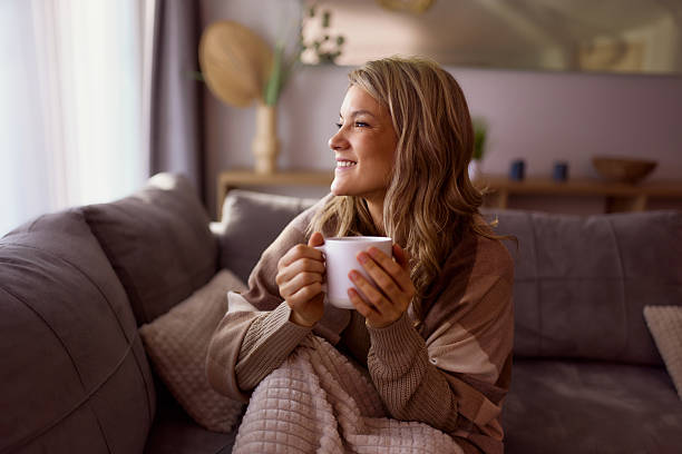 istock Happy woman day dreaming during coffee time on sofa at home. 2209701650