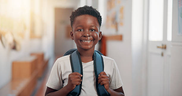 istock Smile, backpack and portrait of black child in school for learning, development or growth on campus. Pride, kid and face of African boy student in hallway for education, studying or lesson at academy 2209701874