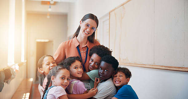 istock School, portrait and children hugging teacher for bonding, learning and education development. Happy, connection and kids embracing woman educator for greeting or welcome at kindergarten academy. 2209701907