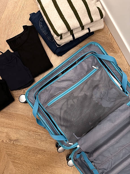 istock Clothes stacked next to a open suitcase from above ready to be placed 2209701930