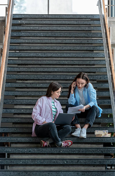 istock Young women studying together using a laptop and books, while sitting on the university stairs 2209704152