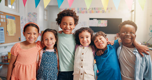 istock Portrait, education and hug with students in classroom for child development, future and learning. Academy, growth and scholarship with group of kids in school for knowledge, lesson and study 2209704634