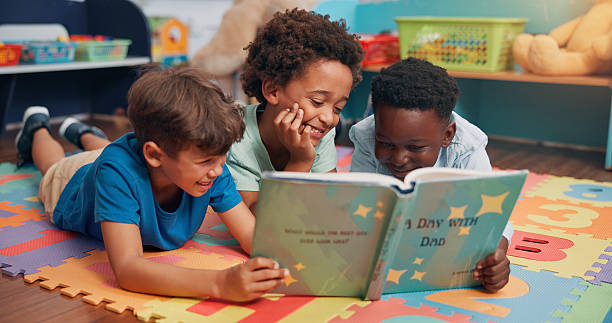 istock Boys, reading and friends on carpet, school and learning with education, relax and bonding together. Group, storytelling and children in classroom, literacy knowledge and happiness with break 2209704750