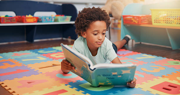 istock African boy, book and floor in classroom for development, storytelling and knowledge at academy. Child, learning and study on mat for scholarship, reading and info with course at elementary school 2209704856