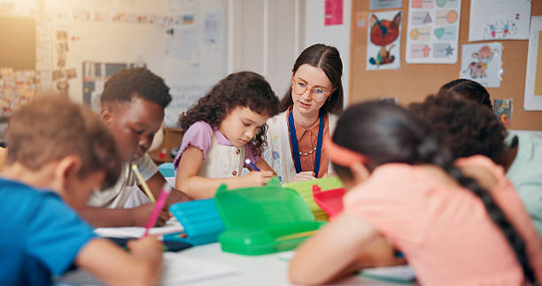 istock Writing, education and teacher helping children in classroom for language development, learning or growth. Notebook, advice and woman educator with kid students for lesson at elementary school. 2209704968