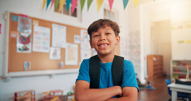 istock Arms crossed, student and education with boy in classroom for learning, future and youth. Scholarship, academy and growth with portrait of kid in school for child development, knowledge and lesson 2209704972