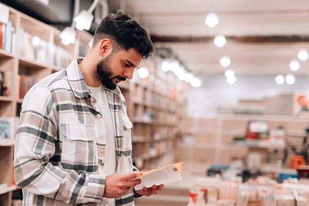istock Young man reading a book in a bookstore, enjoying the quiet atmosphere 2209713284