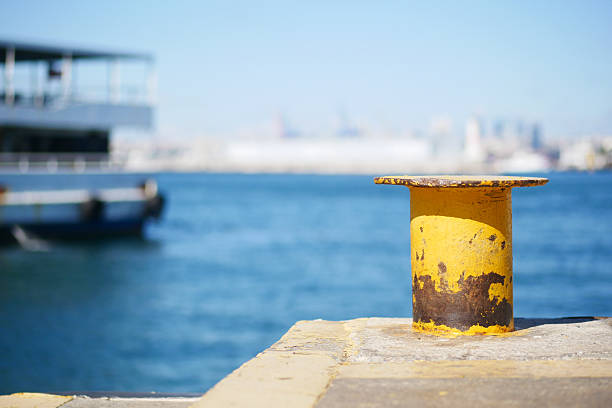 A vibrant yellow mooring post stands out vividly against the serene blue water surrounding it