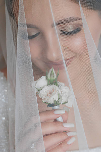 istock A bride is wearing a veil and holding a white flower 2209715161