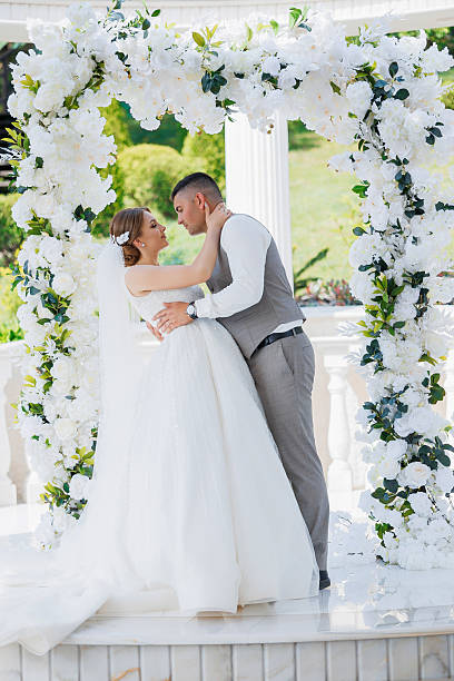 istock A bride and groom are kissing under a white arch 2209715778