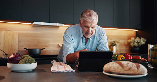 istock Senior man, tablet and search with recipe tutorial, dinner method or online guide in home. Learning, instructions and mature person in kitchen with healthy ingredients, diet or steps in meal prep 2209716939