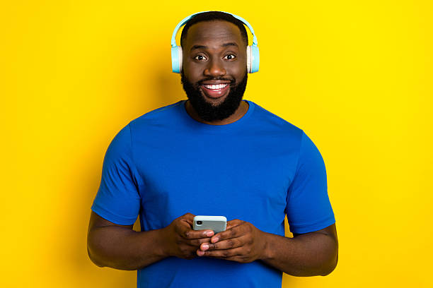 istock Portrait of attractive cheerful guy listening hit using device chart melody isolated over bright yellow color background 2209721232