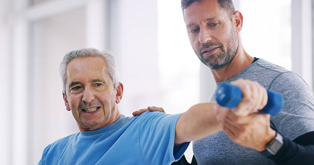 istock Elderly person, physiotherapy and man in office for help, therapy and arm exercise for healing. Senior patient, chiropractor and weight in practice for muscle care, strengthen shoulder and healthcare 2209721380