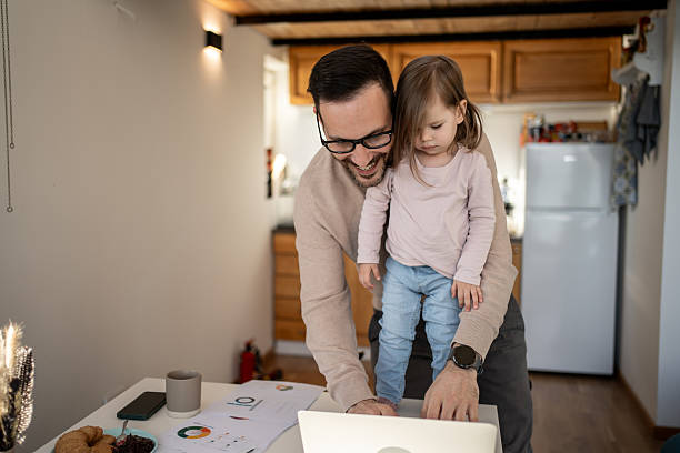 istock Father working from home while holding his daughter in his arms 2209724640