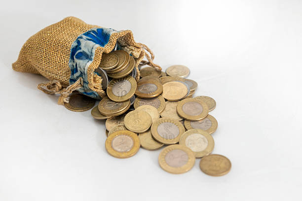 istock Burlap Sack Spilling Variety of Coins on White Surface 2209726182