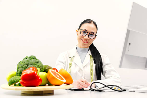 istock A nutritionist takes notes and works at a computer in a bright medical office. Fresh vegetables and fruits are on the table. 2209729047