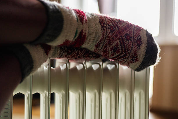 istock women's legs in socks near a heater 2209729843