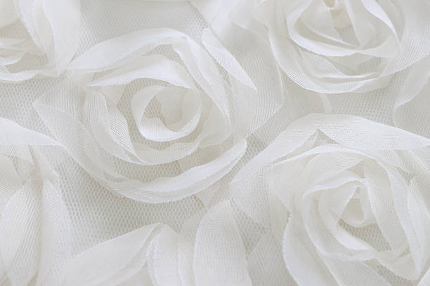 Top view of soft white fabric roses arranged in a delicate floral pattern. Ideal romantic background for wedding, bridal, or love-themed design. Minimal pastel texture with copy space.