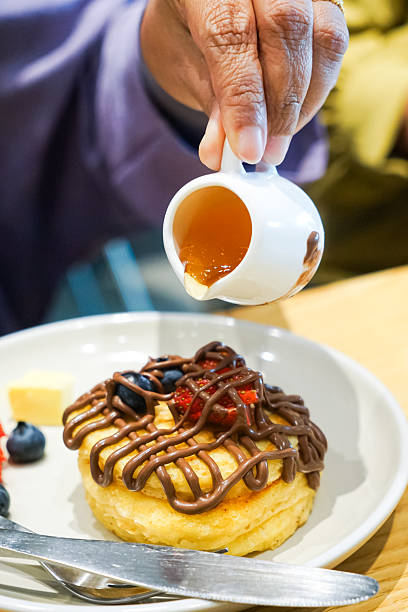 Pouring Syrup Onto A Plate Of Gourmet Pancakes