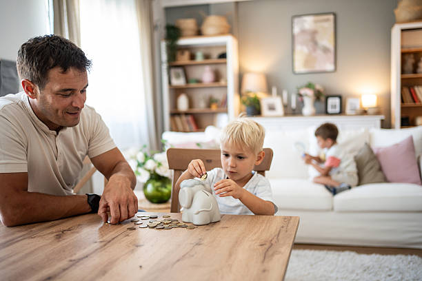 istock Father teaching son about saving money using piggy bank 2209737489