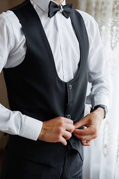 istock A man in a black vest and white shirt is adjusting his tie 2209739821