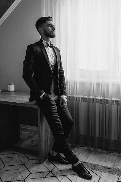 istock A man in a suit and tie is standing in front of a window 2209740191