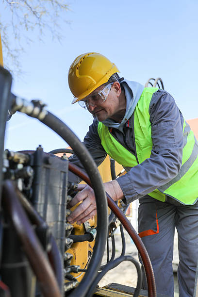 istock Senior man (50+) repairing hydraulic system on construction machinery. Concept: road construction equipment, technician, hydraulic maintenance 2209741916