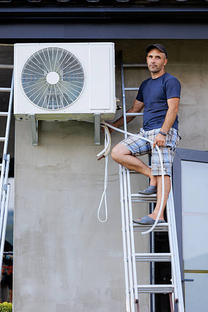 istock A man is standing on a ladder next to an air conditioner 2209742151