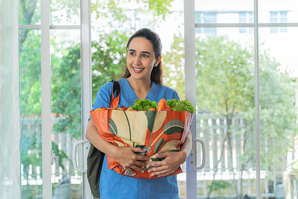 Smiling Nurse Returning Home with Fresh Groceries in a Reusable Bag