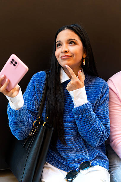 Young latin woman taking a selfie and thinking about a caption