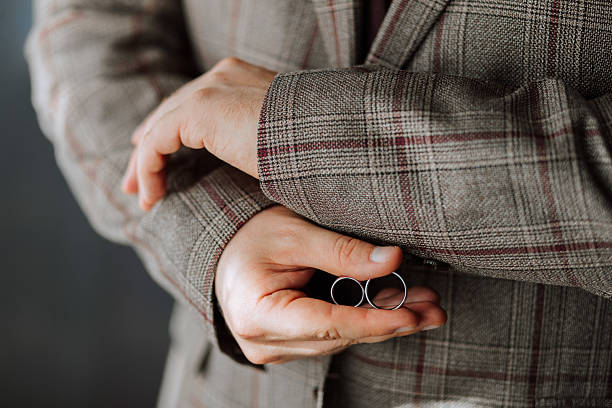 istock A man is wearing a plaid jacket and holding two wedding rings in his hand 2209751321