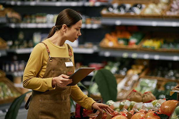 istock Grocery Store Employee Checking Fresh Produce Display 2209754017