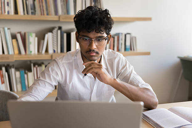istock Focused handsome Indian student man studying online at laptop 2209755118