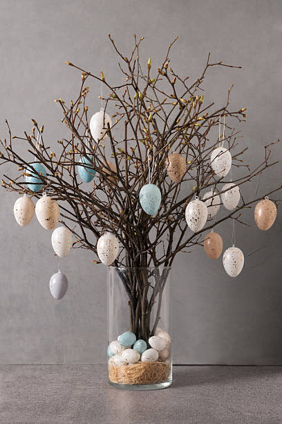 istock Easter tree decorated white and beige eggs in dark vase on gray background. 2209757020