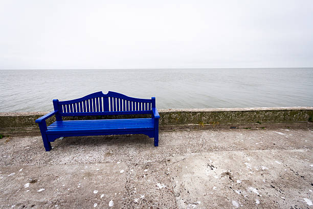 Lonely blue bench on a concrete pier under a cloudy sky in Nida Lithuania