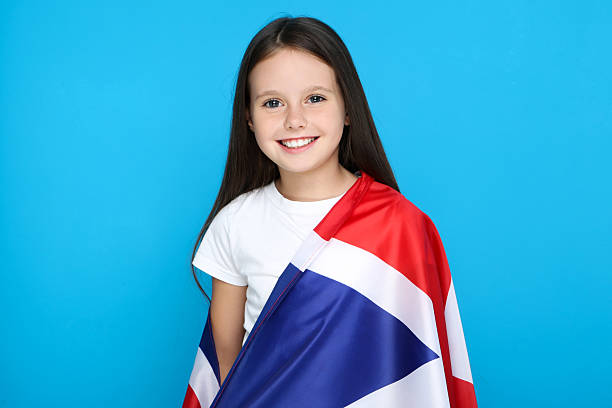 istock Young girl wrapped in british flag on blue background 2209762480
