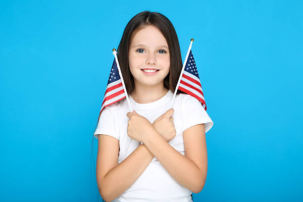 istock Young girl holding american flags on blue background 2209762796