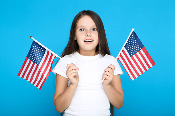 istock Young girl holding american flags on blue background 2209763434