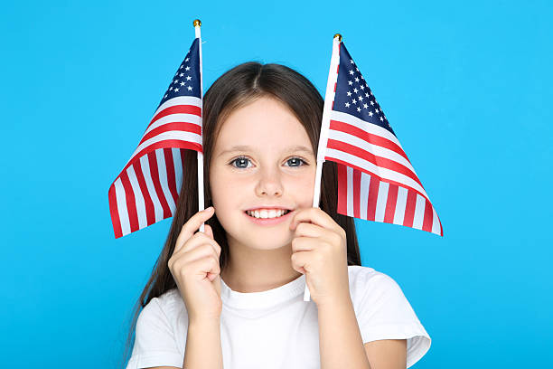 istock Young girl holding american flags on blue background 2209763864