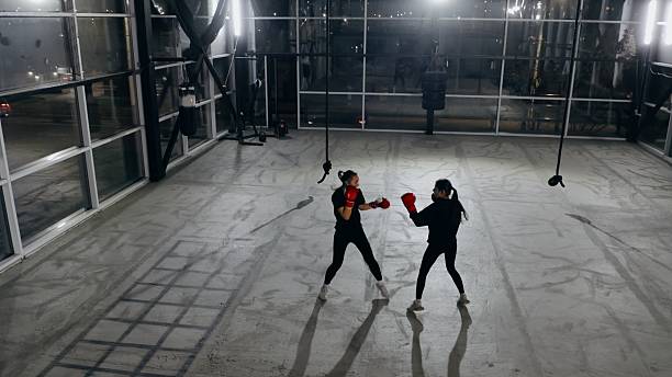 istock Two female athletes boxing in empty gym at night 2209766648