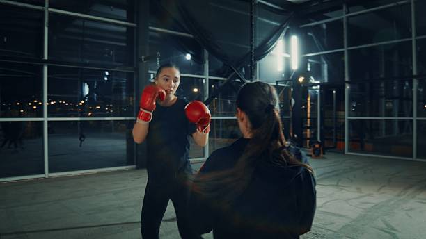 istock Two young women practicing boxing punches in a gym at night 2209767456