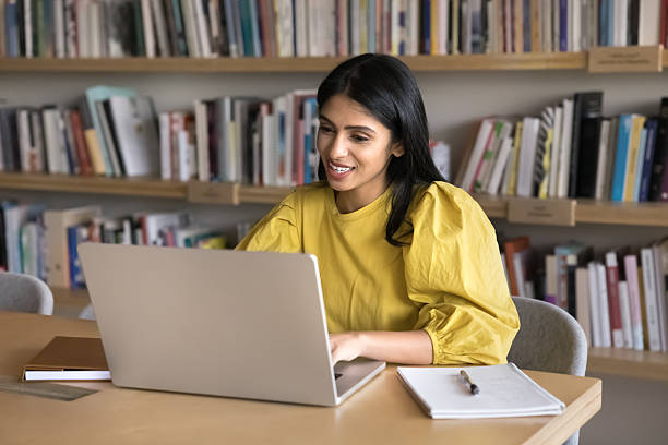 istock Positive young Indian student woman typing on laptop in library 2209767920