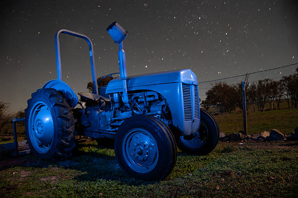 A classic grey Ferguson tractor positioned in a rural paddock beneath a canopy of stars.