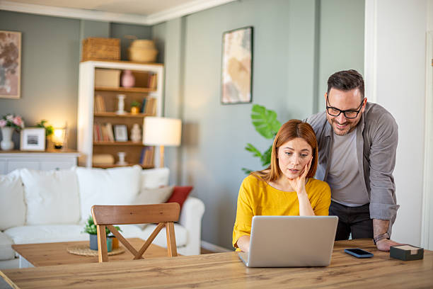 istock Couple working from home using laptop in living room 2209770382