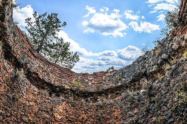 old rusty chimney pipe and rusty tank hatch against the blue sky and clouds