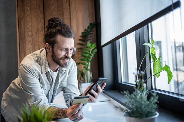 istock Young man making online payment using credit card and smartphone at home 2209775148