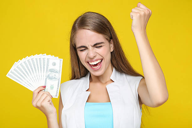 istock Beautiful woman holding dollar banknotes on yellow background 2209776087