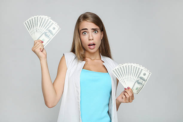 istock Beautiful woman holding dollar banknotes on grey background 2209776297