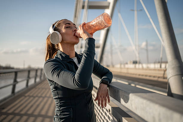 istock Young sportswoman drinking water on bridge after training 2209777425