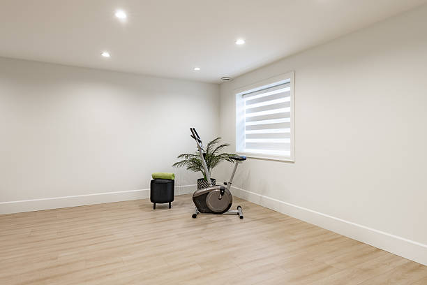 basement recreation room with stationary bike fitness exercise area with bar fridge sink butler pantry countertop space for entertaining or games open and spacious sparsely decorated with hardwood floors and black cabinets